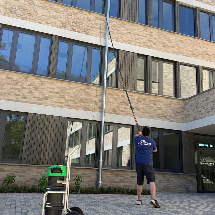 Mann reinigt Fenster einer modernen Bürogebäudefassade